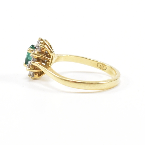 460 - An 18ct gold emerald and diamond cluster ring.  The ring set with a central oval cut emerald framed ... 