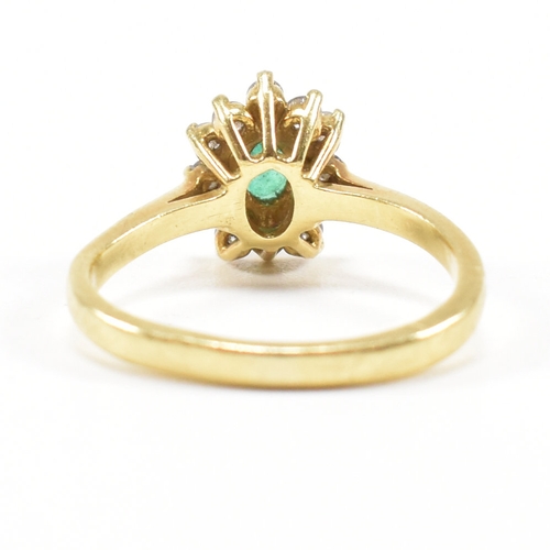 460 - An 18ct gold emerald and diamond cluster ring.  The ring set with a central oval cut emerald framed ... 