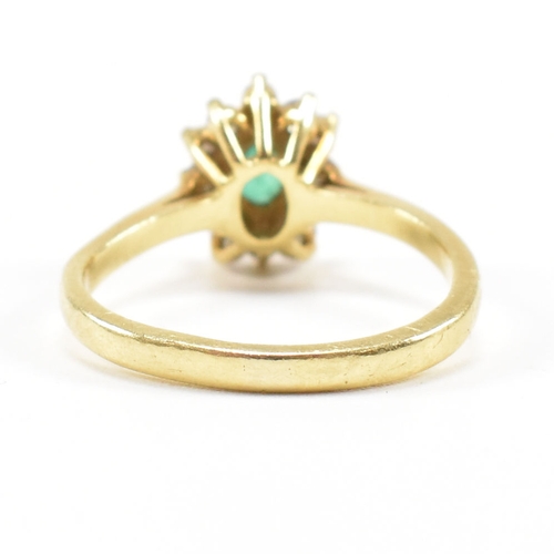 460 - An 18ct gold emerald and diamond cluster ring.  The ring set with a central oval cut emerald framed ... 