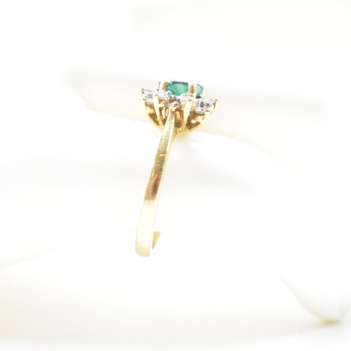 460 - An 18ct gold emerald and diamond cluster ring.  The ring set with a central oval cut emerald framed ... 