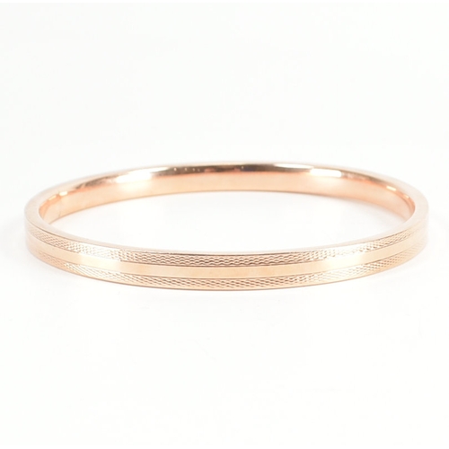 480 - A 9ct rose gold etched design bangle armlet. The bracelet / arm band of circular reverse D form havi... 