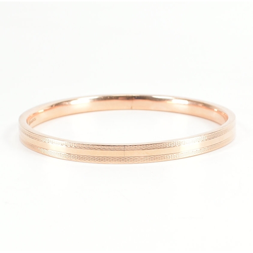 480 - A 9ct rose gold etched design bangle armlet. The bracelet / arm band of circular reverse D form havi... 