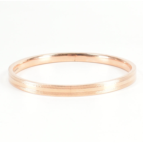 480 - A 9ct rose gold etched design bangle armlet. The bracelet / arm band of circular reverse D form havi... 