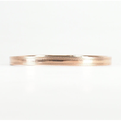 480 - A 9ct rose gold etched design bangle armlet. The bracelet / arm band of circular reverse D form havi... 