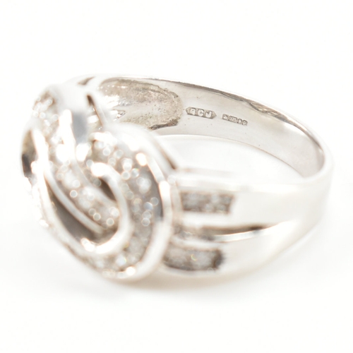 490 - A hallmarked 9ct white gold and diamond knot design ring. The ring being set throughout with round c... 