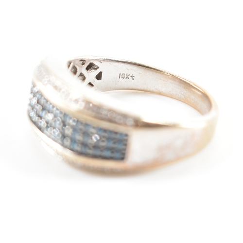 486 - A white gold blue and white diamond ring. The ring having a central band of blue stones flanked by w... 