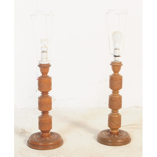 606 - A pair of large 20th century hand carved and turned wooden table lamps having floral and foliate car... 