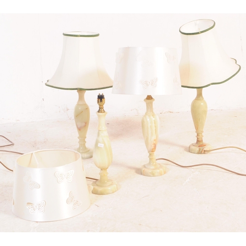 619 - A group of four mid 20th century turned onyx table lamp lights. With light fixings to top, into a ta... 