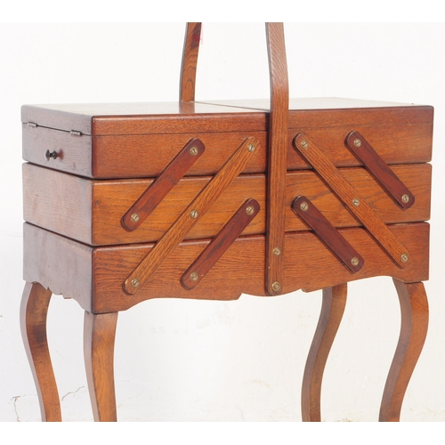715 - A 1950's metamorphic / concertina sewing box on legs.  This dark teak unit has a carry handle to top... 