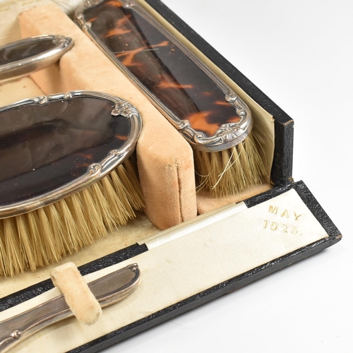 104 - A George V hallmarked silver and tortoiseshell mounted, cased vanity set. The six piece set to inclu... 