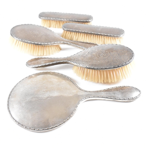 116 - A George V Hallmarked silver mounted five piece vanity set. The set comprised of two hair brushes, t... 