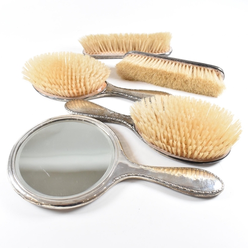 116 - A George V Hallmarked silver mounted five piece vanity set. The set comprised of two hair brushes, t... 