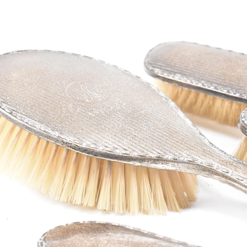 116 - A George V Hallmarked silver mounted five piece vanity set. The set comprised of two hair brushes, t... 