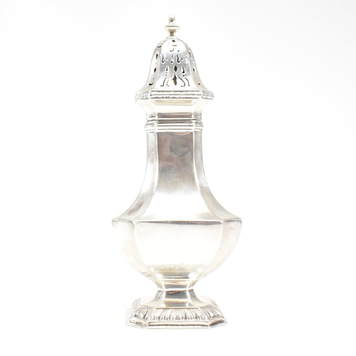 139 - A George V hallmarked silver sugar caster. The caster sitting on a plinth base with repousse decorat... 