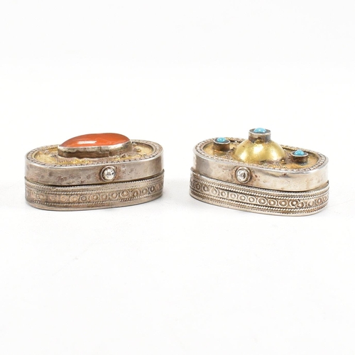 174 - Two Tibetan white metal gem set pill boxes. A white metal and hilt box set with an oval carnelian ca... 