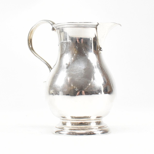 175 - A Victorian hallmarked silver creamer jug. The jug on a round foot rising to baluster body with scro... 