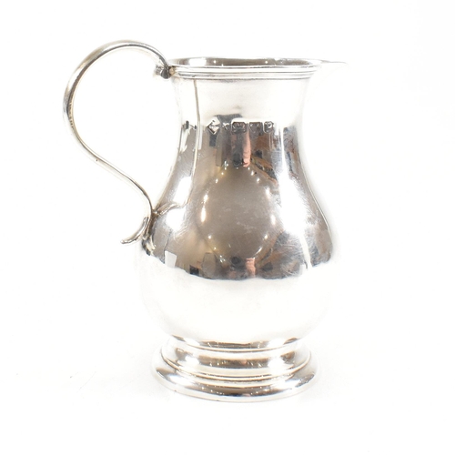 175 - A Victorian hallmarked silver creamer jug. The jug on a round foot rising to baluster body with scro... 