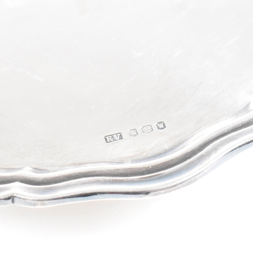 20 - A Mid-century hallmarked silver salver. The salver being raised on three scrolled feet and having a ... 