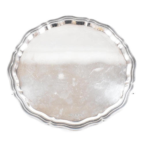 20 - A Mid-century hallmarked silver salver. The salver being raised on three scrolled feet and having a ... 