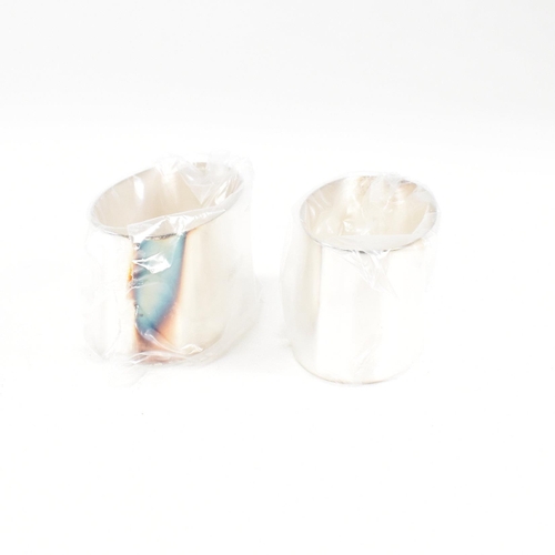 43 - A 1990s pair of cased hallmarked silver napkin rings. The napkin rings of oblong form and having ori... 