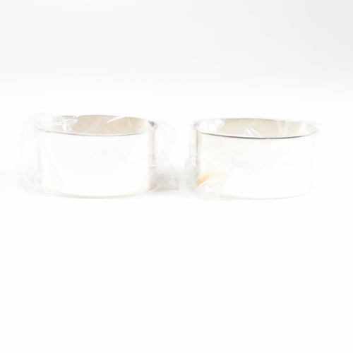 43 - A 1990s pair of cased hallmarked silver napkin rings. The napkin rings of oblong form and having ori... 