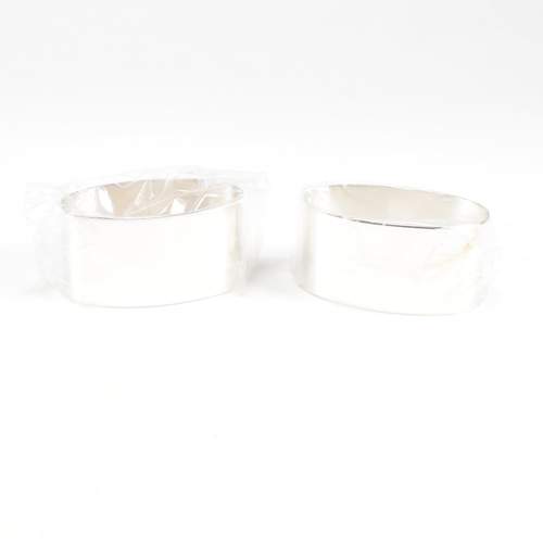 43 - A 1990s pair of cased hallmarked silver napkin rings. The napkin rings of oblong form and having ori... 