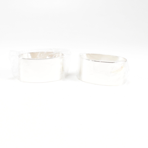 43 - A 1990s pair of cased hallmarked silver napkin rings. The napkin rings of oblong form and having ori... 