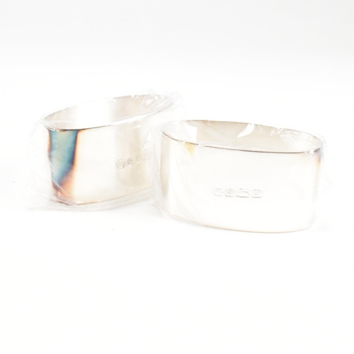 43 - A 1990s pair of cased hallmarked silver napkin rings. The napkin rings of oblong form and having ori... 