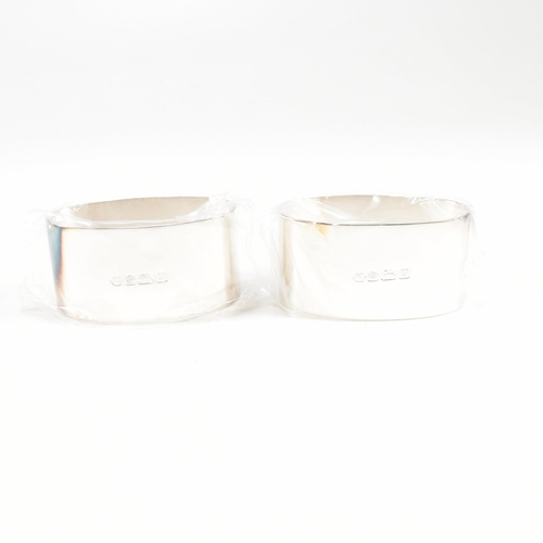 43 - A 1990s pair of cased hallmarked silver napkin rings. The napkin rings of oblong form and having ori... 