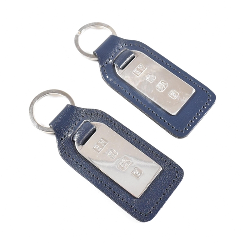 55 - Two 1990s hallmarked silver and leather tag keyrings. The silver tags backed with navy blue leather ... 