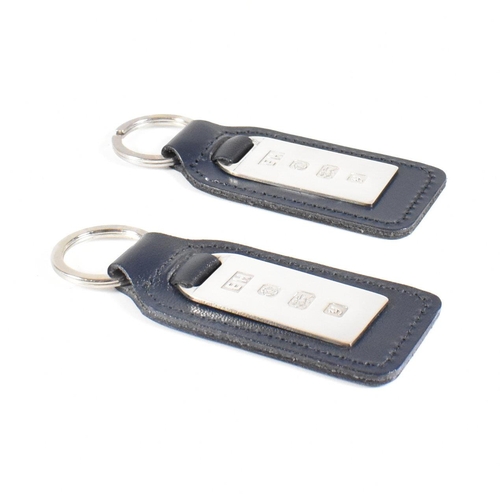 55 - Two 1990s hallmarked silver and leather tag keyrings. The silver tags backed with navy blue leather ... 