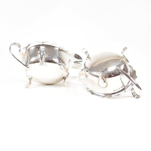 77 - A pair of mid-centuryÿ hallmarked silver sauce boats. The pair having three hoof feet rising to jugu... 