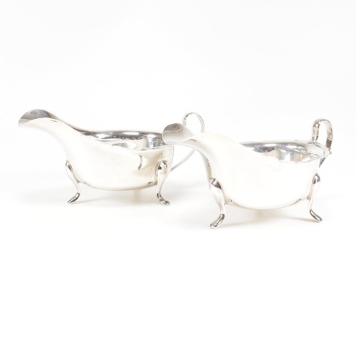 77 - A pair of mid-centuryÿ hallmarked silver sauce boats. The pair having three hoof feet rising to jugu... 