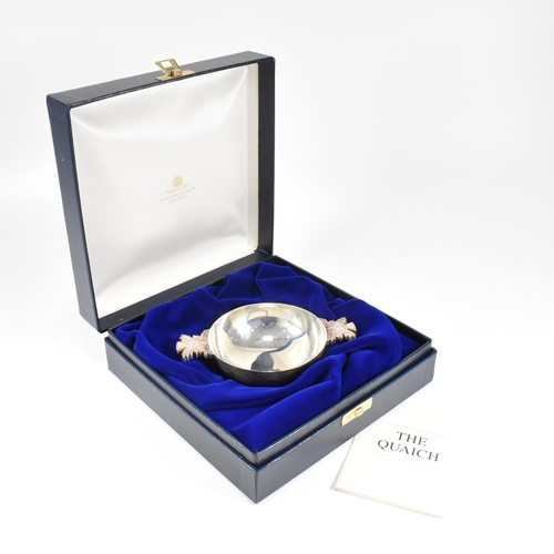 85 - A 1990s cased hallmarked silver quaich. The quaich having adjacent moulded handles in the form of th... 