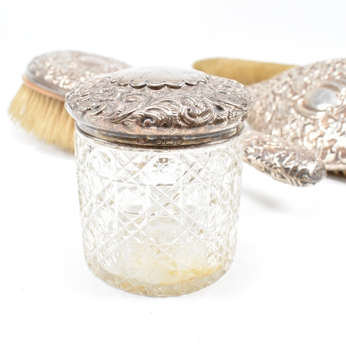 93 - A Victorian four piece hallmarked silver mounted dressing table vanity set and two silver topped jar... 