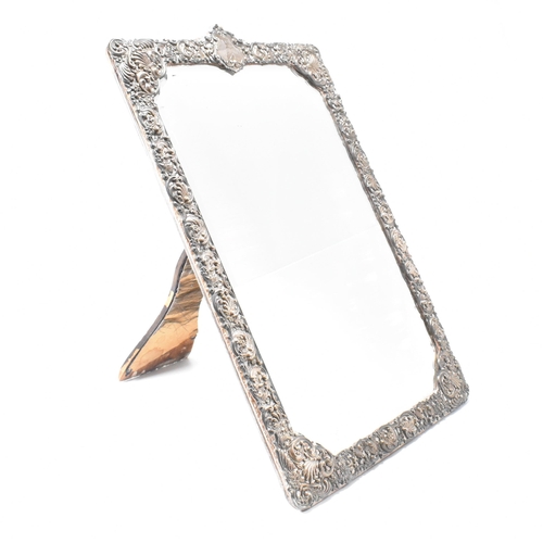 94 - An Edwardian hallmarked silver mounted mirror. The easel backed frame having a floral repouss desig... 