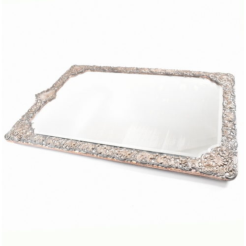 94 - An Edwardian hallmarked silver mounted mirror. The easel backed frame having a floral repouss desig... 