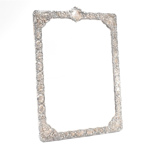 94 - An Edwardian hallmarked silver mounted mirror. The easel backed frame having a floral repouss desig... 