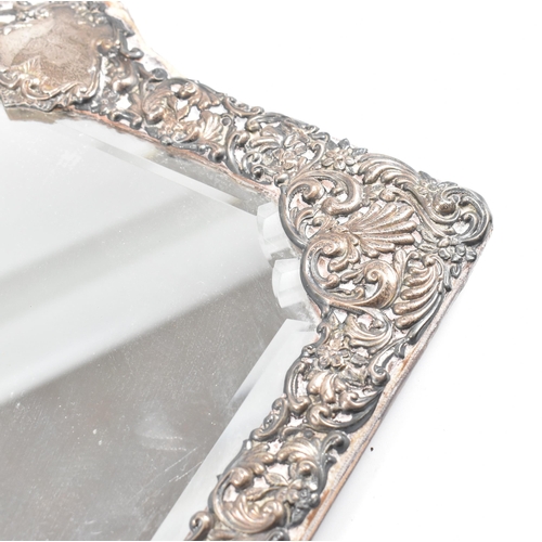 94 - An Edwardian hallmarked silver mounted mirror. The easel backed frame having a floral repouss desig... 