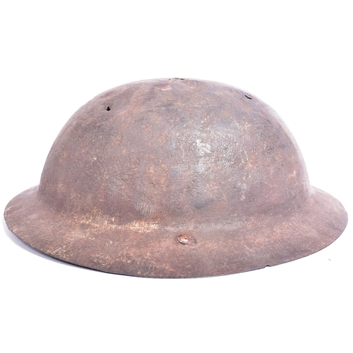 342 - A WWI First World War British Army steel brodie helmet. A combat / battle damaged example with a raw... 