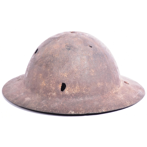 342 - A WWI First World War British Army steel brodie helmet. A combat / battle damaged example with a raw... 