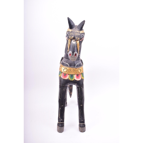 257 - A mid 20th century hand painted Indian style wooden toy horse. The horse black, with gilt highlights... 