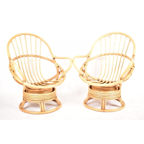 313 - A pair of retro 20th century bamboo and wicker / cane swivel armchair / egg chairs. Each chair havin... 