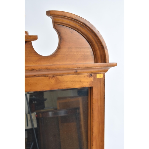 342 - A vintage 20th century American pine hanging mirror. The mirror having a carved pediment top with ce... 