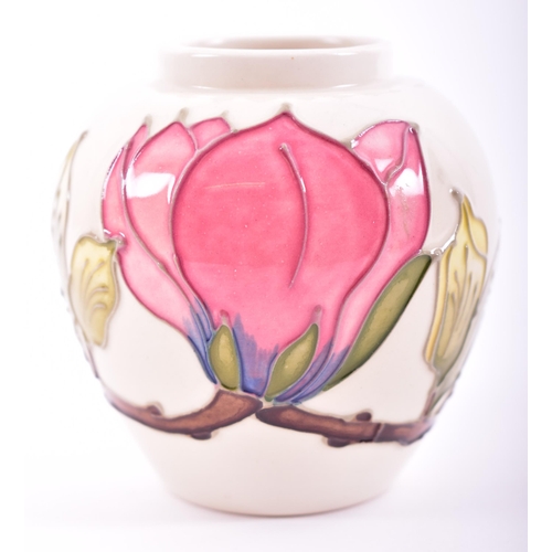 81 - A late 20th century Moorcroft Pottery vase in the Magnolia pattern. The vase of cream ground with pi... 