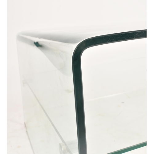 454 - A 20th century British design curved glass two tier coffee table / low table. The table having a one... 