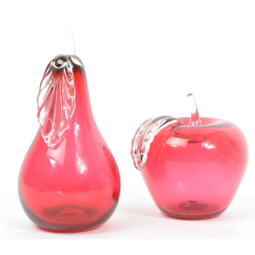 196 - A Bristol Blue Glass apple in a cranberry colour along with a pear also in cranberry. Both are signe... 