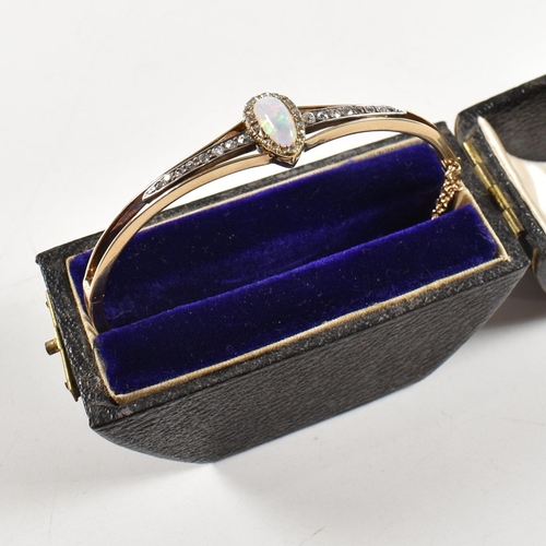 10 - A cased early late Victorian Edwardian opal and diamond hinged bangle. The bangle having a pear cut ... 