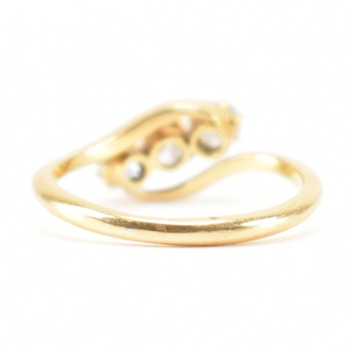 553 - A hallmarked 18ct gold and diamond three stone ring. The crossover ring being set with three graduat... 