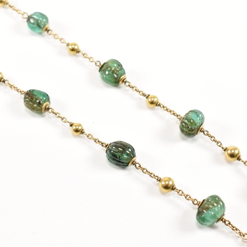 58 - A gold and carved emerald bead necklace. The necklace strung with 15 carved emerald beads having gol... 